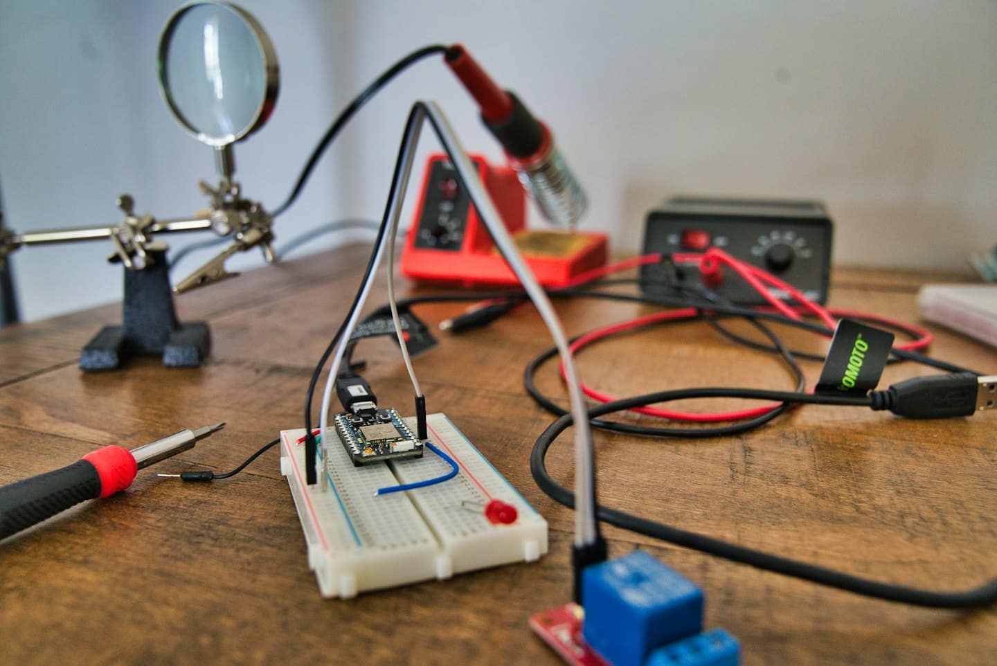 Electronics workbench with breadboard, tools, and components for a DIY project.